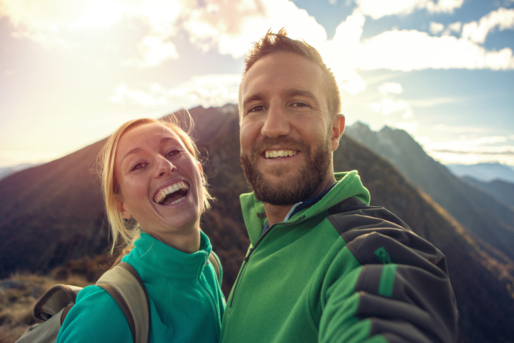 Couple standing on hilltop enjoying scenic mountain view together.