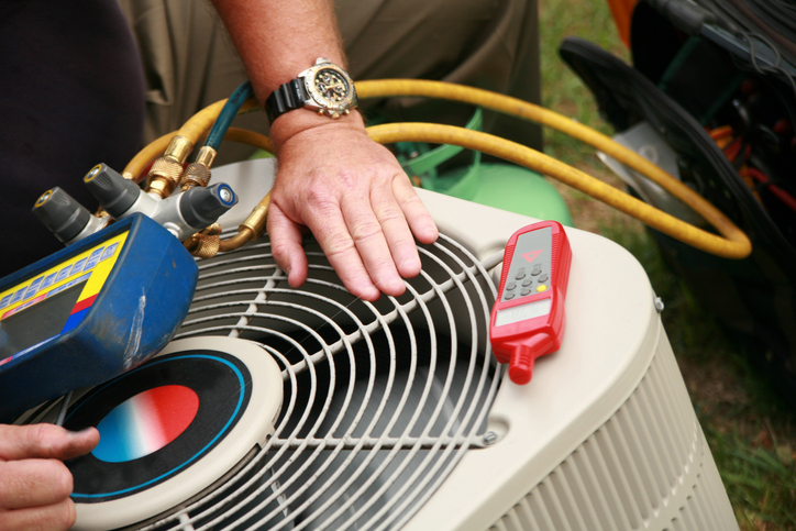 Technician performing maintenance on an outdoor air conditioning unit.