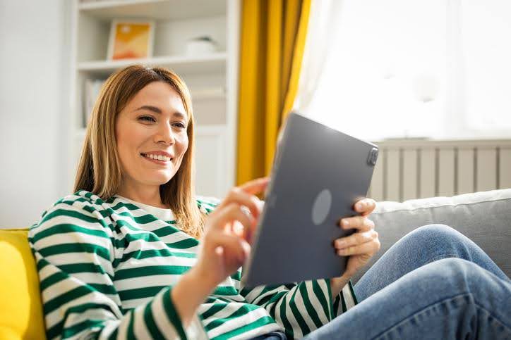 Smiling woman looking at a tablet, exploring American Standard dealer services.