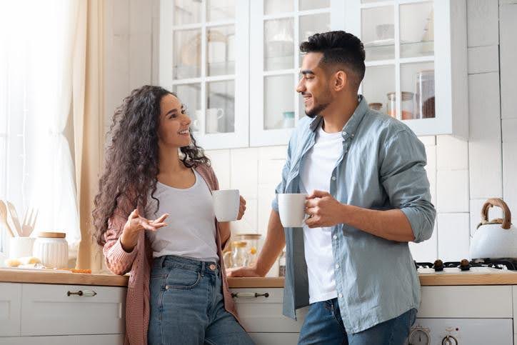 Couple sitting together indoors, enjoying a warm drink in a comfortable, climate-controlled home.