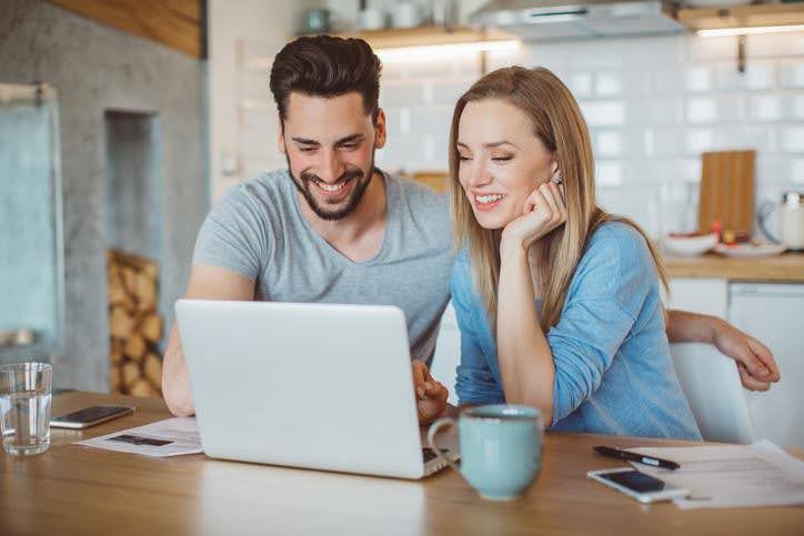 Couple sitting together, looking at a laptop while researching new HVAC systems.