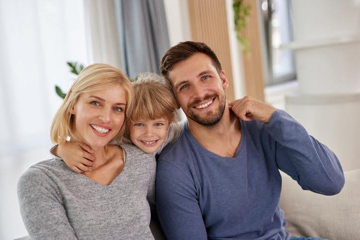 Family enjoying reliable home heating service Happy family sitting together indoors, enjoying warmth and comfort from a working heating system.