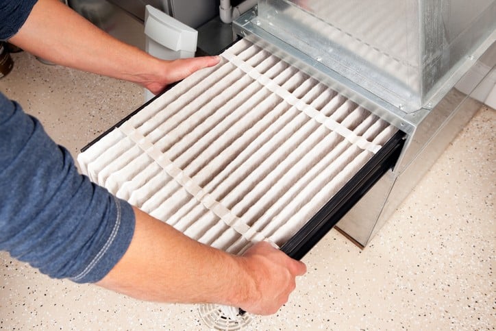 Person changing a dirty air conditioning filter in a home HVAC system.