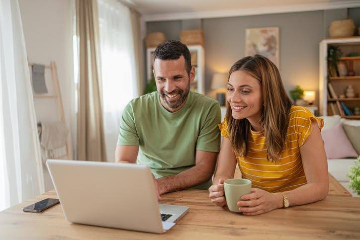 Couple sitting together, looking at a laptop while researching a new AC system in Mansfield.