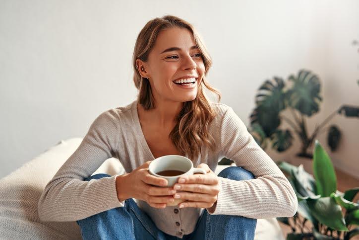 Girl enjoying a warm cup of tea in a cozy room with a new heating system.