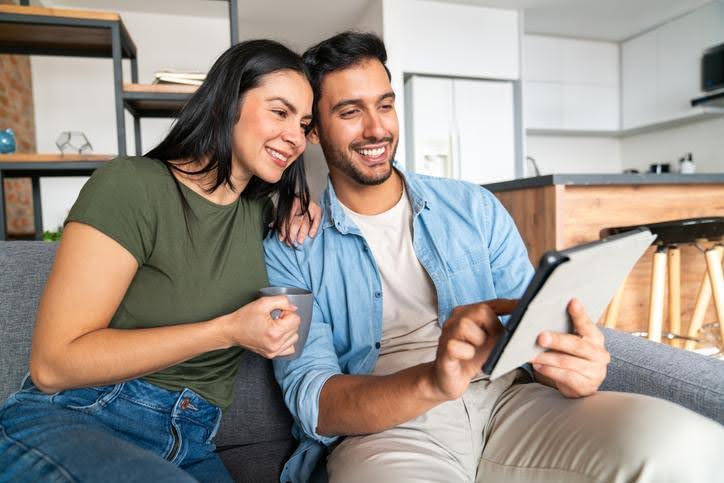 Couple sitting together, reviewing a service plan on a tablet device.