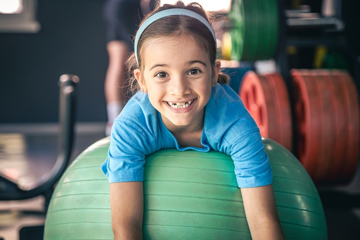 Girl from Gym Fun Kit smiling while riding in a colorful hot air balloon