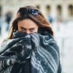 Girl wrapped in a shawl feeling cold while furnace is running