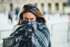 Girl wrapped in a shawl feeling cold while furnace is running